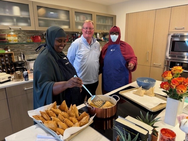 A group of people next to a stove cooking traditional Somali sambusas 